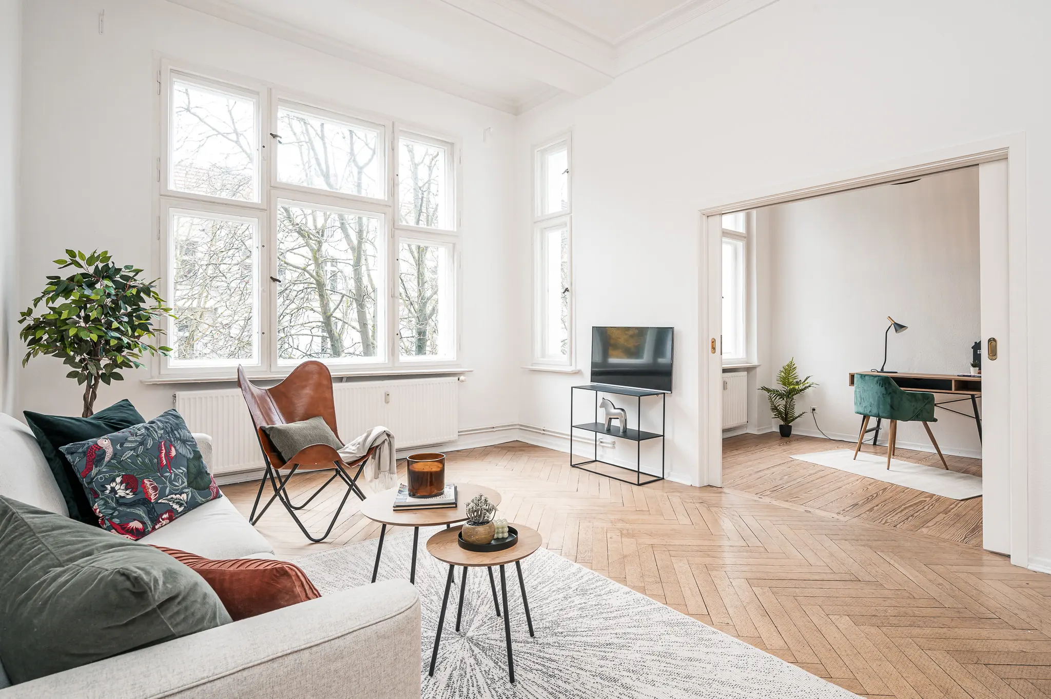 Gestagtes Wohnzimmer mit Fischgrätparkett und Blick ins Arbeitszimmer